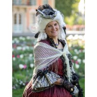 Eine Frau in barockem Kost&uuml;m mit wei&szlig;er Per&uuml;cke und rotem Kleid steht l&auml;chelnd im Freien vor einem Blumenbeet., &copy; Touristik und Marketing GmbH