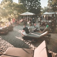 Menschen entspannen an einem sonnigen Stadtstrand in Stuttgart. Liegestühle und Sonnenschirme bieten eine gemütliche Atmosphäre im Sand., © Classic Rock Café Gastronomie- Betriebs GmbH
