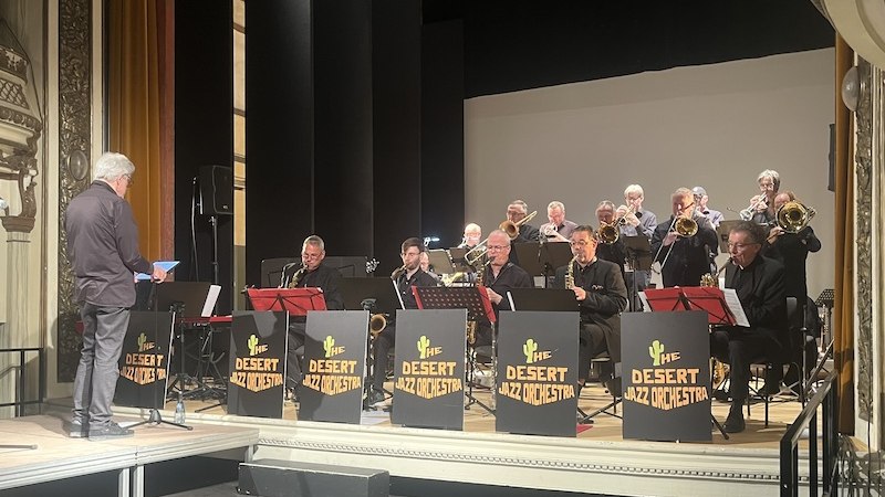 Das Desert Jazz Orchestra spielt auf einer B&uuml;hne unter der Leitung eines Dirigenten. Die Musiker tragen schwarze Kleidung und spielen Blasinstrumente., &copy; Touristik Bad Wildbad GmbH