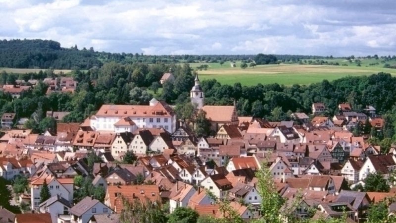 Panoramablick auf Waldenbuch mit roten Dächern, einer Kirche und grüner Landschaft im Hintergrund., © Graphic Design Albig Panoramablick auf Waldenbuch mit roten Dächern, einer Kirche und grüner Landschaft im Hintergrund., © Graphic Design Albig