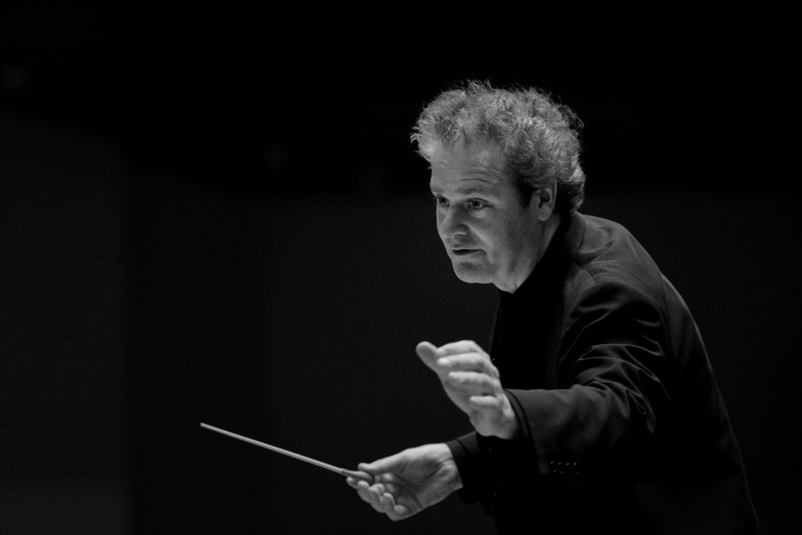Ein Dirigent in Aktion, hält einen Taktstock in der Hand. Schwarz-weiß Foto mit Fokus auf seine konzentrierte Mimik., © Ines Fuchs