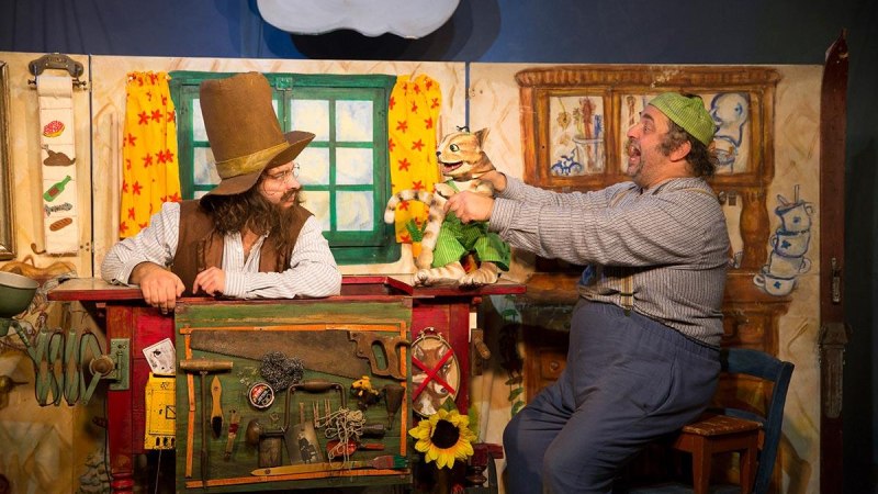 Theaterszene aus "Pettersson kriegt Weihnachtsbesuch" mit zwei Schauspielern und einer Katze als Puppe in einer gemütlichen Kulisse., © Pettersson kriegt Weihnachtsbesuch - Theater Kuckucksheim, Foto: Andreas Riedel Theaterszene aus "Pettersson kriegt Weihnachtsbesuch" mit zwei Schauspielern und einer Katze als Puppe in einer gemütlichen Kulisse., © Pettersson kriegt Weihnachtsbesuch - Theater Kuckucksheim, Foto: Andreas Riedel