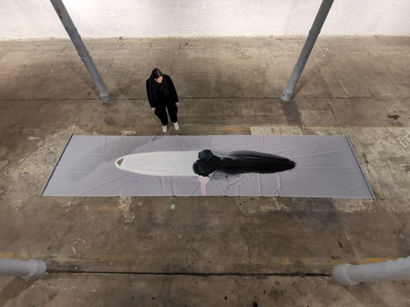 Eine Person steht in einer Ausstellungshalle und betrachtet ein langes, abstraktes Kunstwerk auf dem Boden., &copy; Kunstzentrum Karlskaserne