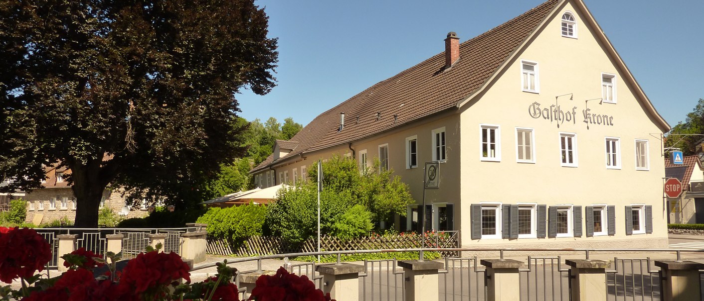 Der Gasthof Krone, ein großes Gebäude mit gelber Fassade und braunem Dach, umgeben von Bäumen und einem Garten. Ein Stoppschild ist sichtbar., © Gasthof Krone, Matthias Gugeler Der Gasthof Krone, ein großes Gebäude mit gelber Fassade und braunem Dach, umgeben von Bäumen und einem Garten. Ein Stoppschild ist sichtbar., © Gasthof Krone, Matthias Gugeler