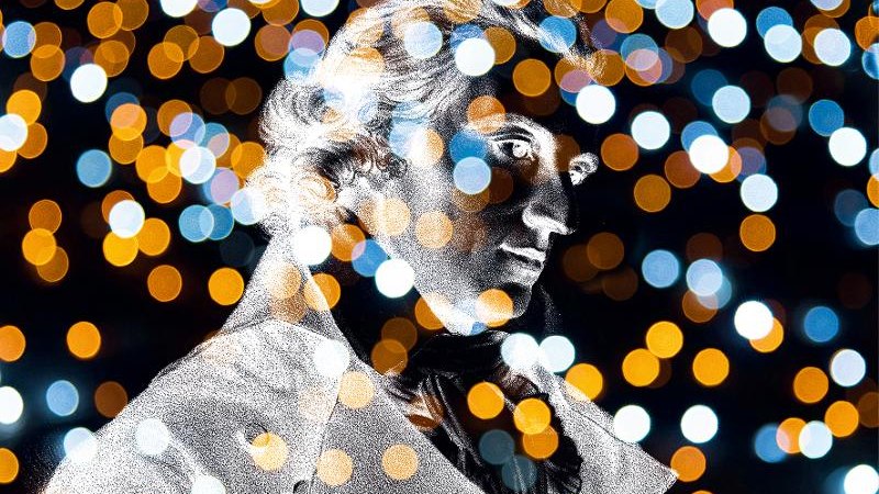 Eine Statue vor einem Hintergrund aus unscharfen, bunten Lichtern, die eine festliche Atmosphäre erzeugen., © Backnang Eine Statue vor einem Hintergrund aus unscharfen, bunten Lichtern, die eine festliche Atmosphäre erzeugen., © Backnang