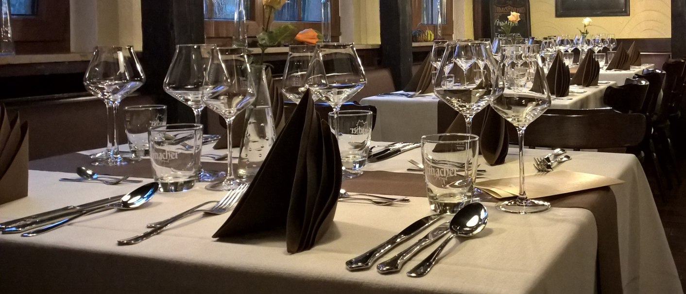 Elegante Tischdekoration in einem Restaurant mit Weingläsern, Besteck und gefalteten Servietten auf weißen Tischdecken., © Wirtshaus zom Schiller Fellbach Elegante Tischdekoration in einem Restaurant mit Weingläsern, Besteck und gefalteten Servietten auf weißen Tischdecken., © Wirtshaus zom Schiller Fellbach