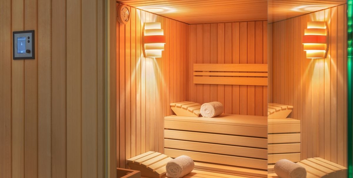 Moderne Sauna mit Holzbänken, Handtüchern und sanfter Beleuchtung. Ein Thermometer ist an der Wand angebracht., © Novum Hospitality Moderne Sauna mit Holzbänken, Handtüchern und sanfter Beleuchtung. Ein Thermometer ist an der Wand angebracht., © Novum Hospitality