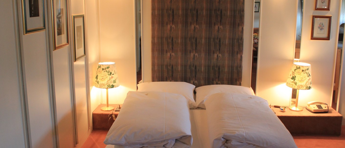 Gemütliches Hotelzimmer mit Doppelbett, zwei Nachttischlampen und dekorativen Bildern an der Wand., © Hotel Spahr Gemütliches Hotelzimmer mit Doppelbett, zwei Nachttischlampen und dekorativen Bildern an der Wand., © Hotel Spahr