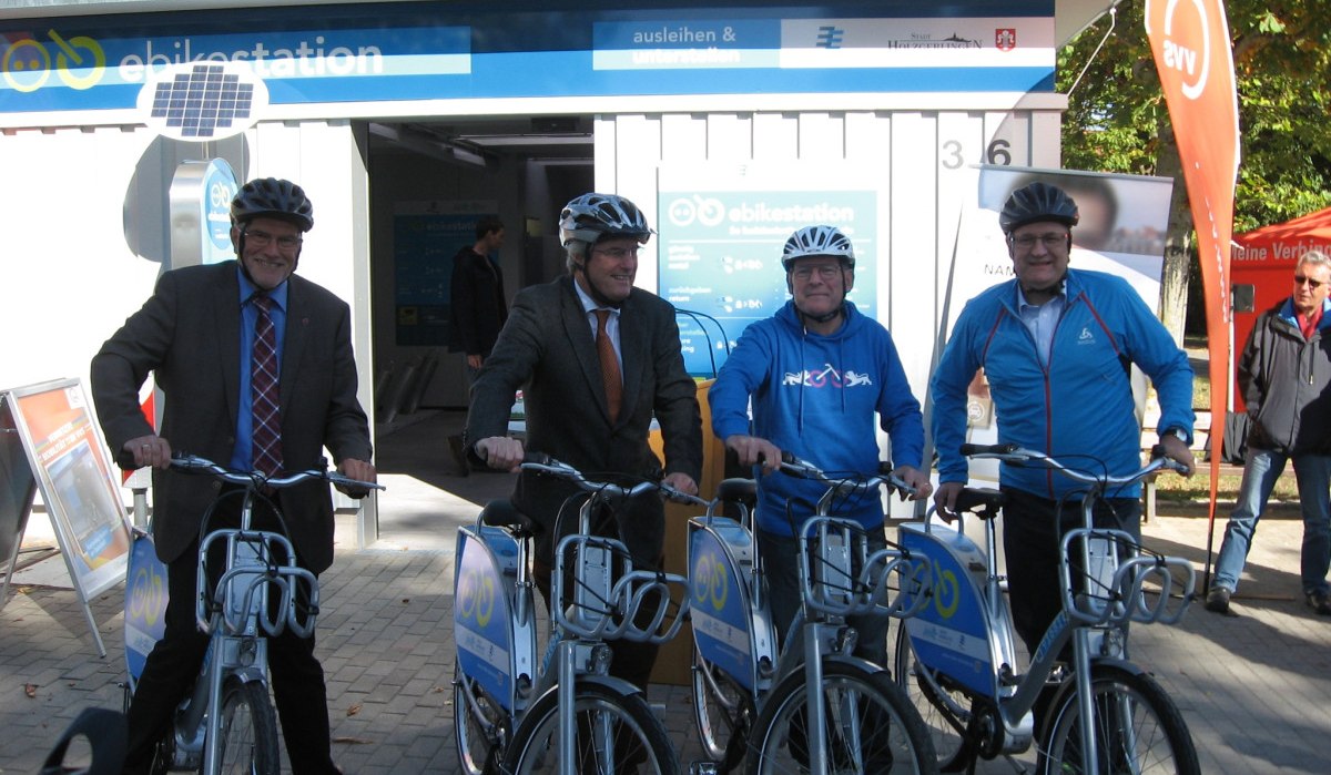Vier Männer mit Helmen posieren mit Pedelecs vor der ebikestation in Holzgerlingen. Im Hintergrund ist die Station mit Solarpanel zu sehen., © Natur.Nah. Schönbuch & Heckengäu Vier Männer mit Helmen posieren mit Pedelecs vor der ebikestation in Holzgerlingen. Im Hintergrund ist die Station mit Solarpanel zu sehen., © Natur.Nah. Schönbuch & Heckengäu