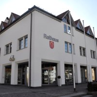 Das Nufringer Rathaus mit weißer Fassade und roten Dächern, zwei Eingängen und einem Wappen an der Wand., © Natur.Nah. Schönbuch & Heckengäu Das Nufringer Rathaus mit weißer Fassade und roten Dächern, zwei Eingängen und einem Wappen an der Wand., © Natur.Nah. Schönbuch & Heckengäu