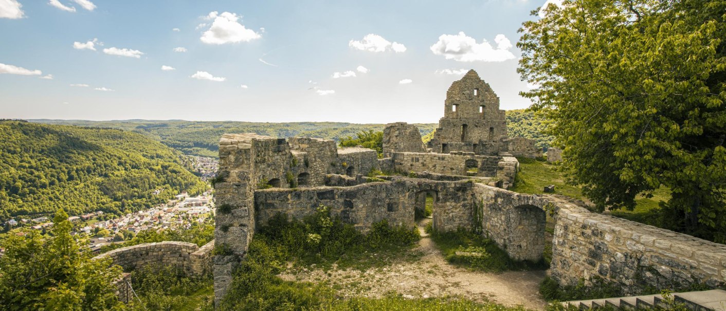 Die Ruine Hohenurach thront über Bad Urach, umgeben von grünen Wäldern und Hügeln unter einem blauen Himmel mit wenigen Wolken., © Stuttgart-Marketing GmbH, Sarah Schmid Die Ruine Hohenurach thront über Bad Urach, umgeben von grünen Wäldern und Hügeln unter einem blauen Himmel mit wenigen Wolken., © Stuttgart-Marketing GmbH, Sarah Schmid