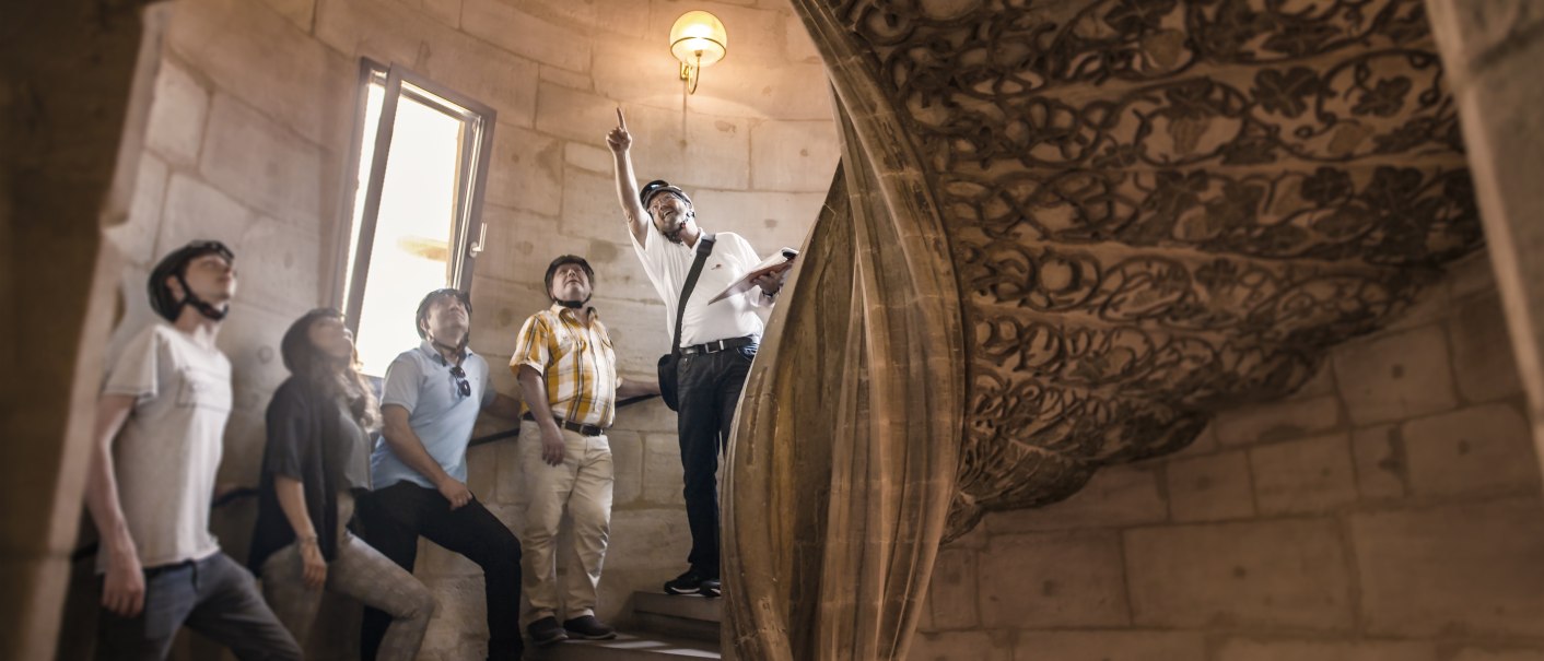 Gruppe von Menschen mit Helmen in einem historischen Gebäude, ein Mann zeigt nach oben. Verzierter Steinbogen im Hintergrund., © Stadtmarketing Göppingen