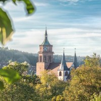 Die Peter und Paul Kirche in Weil der Stadt erhebt sich majestätisch über die herbstliche Landschaft, umgeben von buntem Laub und klarem Himmel., © © Stuttgart-Marketing GmbH, Martina Denker