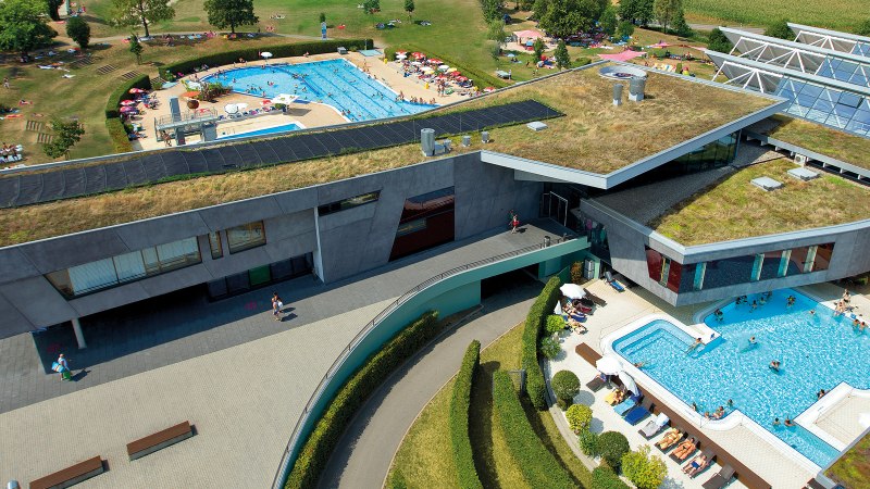 Luftaufnahme des Fildorado mit begr&uuml;ntem Dach, Au&szlig;enpool und Liegewiese. Menschen entspannen und schwimmen bei sonnigem Wetter., &copy; Sport- und Badezentrum Fildorado GmbH