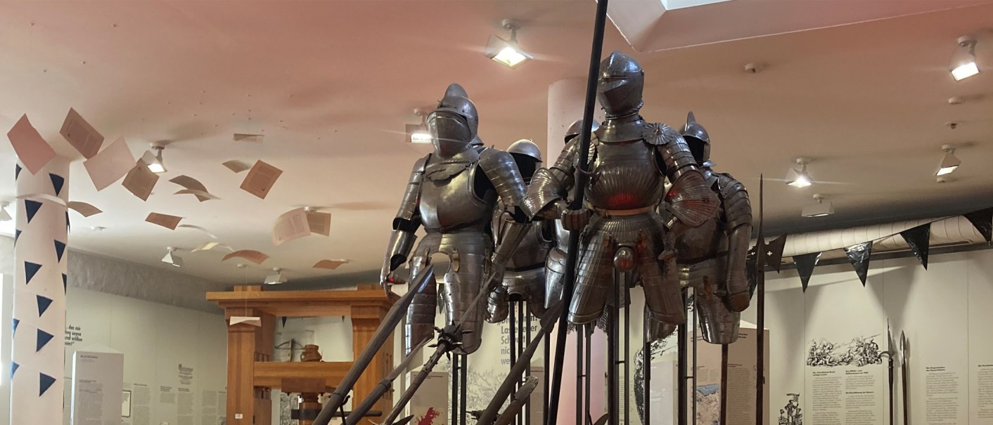 Ritterrüstungen in einer Ausstellung im Deutschen Bauernkriegsmuseum Böblingen. Über ihnen schweben Papierblätter von der Decke., © Stadt Böblingen