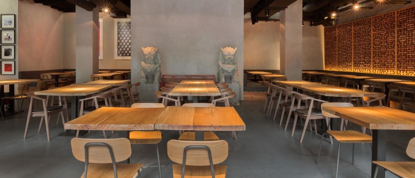 Modernes Restaurant mit Holztischen, Stühlen und asiatischen Dekorationen. Dezente Beleuchtung und kunstvolle Wandgestaltung schaffen eine einladende Atmosphäre., © Breitengrad17, Stuttgart