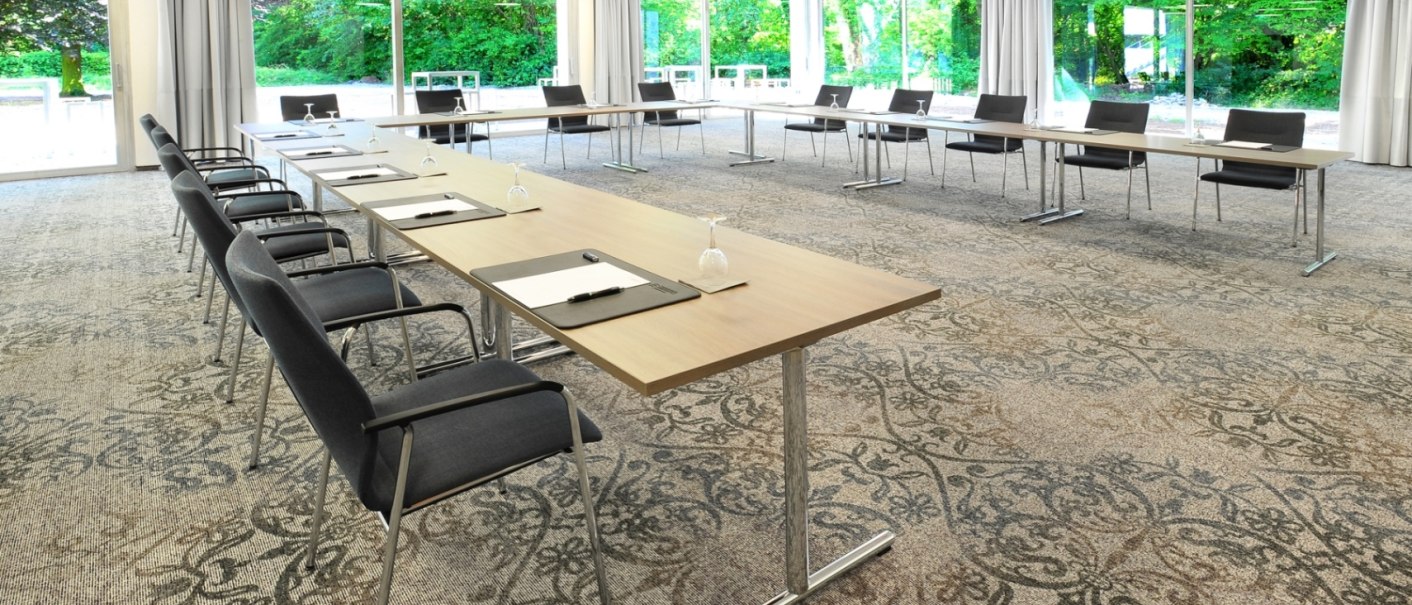 Moderner Konferenzraum mit langen Tischen, Stühlen und großen Fenstern, die einen Blick auf eine grüne Landschaft bieten., © Schlosshotel Monrepos Moderner Konferenzraum mit langen Tischen, Stühlen und großen Fenstern, die einen Blick auf eine grüne Landschaft bieten., © Schlosshotel Monrepos