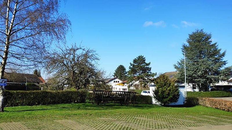 Ein Wohnmobilstellplatz mit B&auml;umen und einem Parkplatzschild. Im Hintergrund sind H&auml;user und ein blauer Himmel zu sehen., &copy; Dieter Schurr, Gasthaus Hirsch