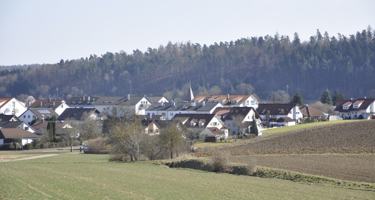 Ländliche Szene mit Häusern in Nufringen, umgeben von Feldern und einem Wald im Hintergrund unter klarem Himmel., © Natur.Nah. Schönbuch & Heckengäu Ländliche Szene mit Häusern in Nufringen, umgeben von Feldern und einem Wald im Hintergrund unter klarem Himmel., © Natur.Nah. Schönbuch & Heckengäu