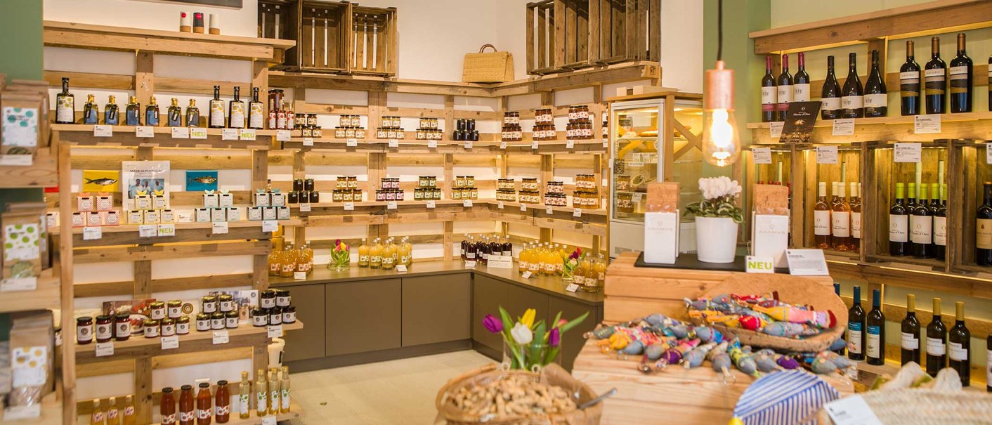 Feinkostladen mit Regalen voller Weinflaschen, Marmeladen und anderen Produkten. Holzkisten und dekorative Elemente schaffen eine gemütliche Atmosphäre., © Benjamin Stollenberg Feinkostladen mit Regalen voller Weinflaschen, Marmeladen und anderen Produkten. Holzkisten und dekorative Elemente schaffen eine gemütliche Atmosphäre., © Benjamin Stollenberg