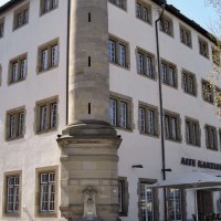 Die Alte Kanzlei in Stuttgart, ein historisches Gebäude mit vielen Fenstern, einem markanten Eckpfeiler und einem Außenbereich mit Sonnenschirmen., © Stuttgart-Marketing GmbH