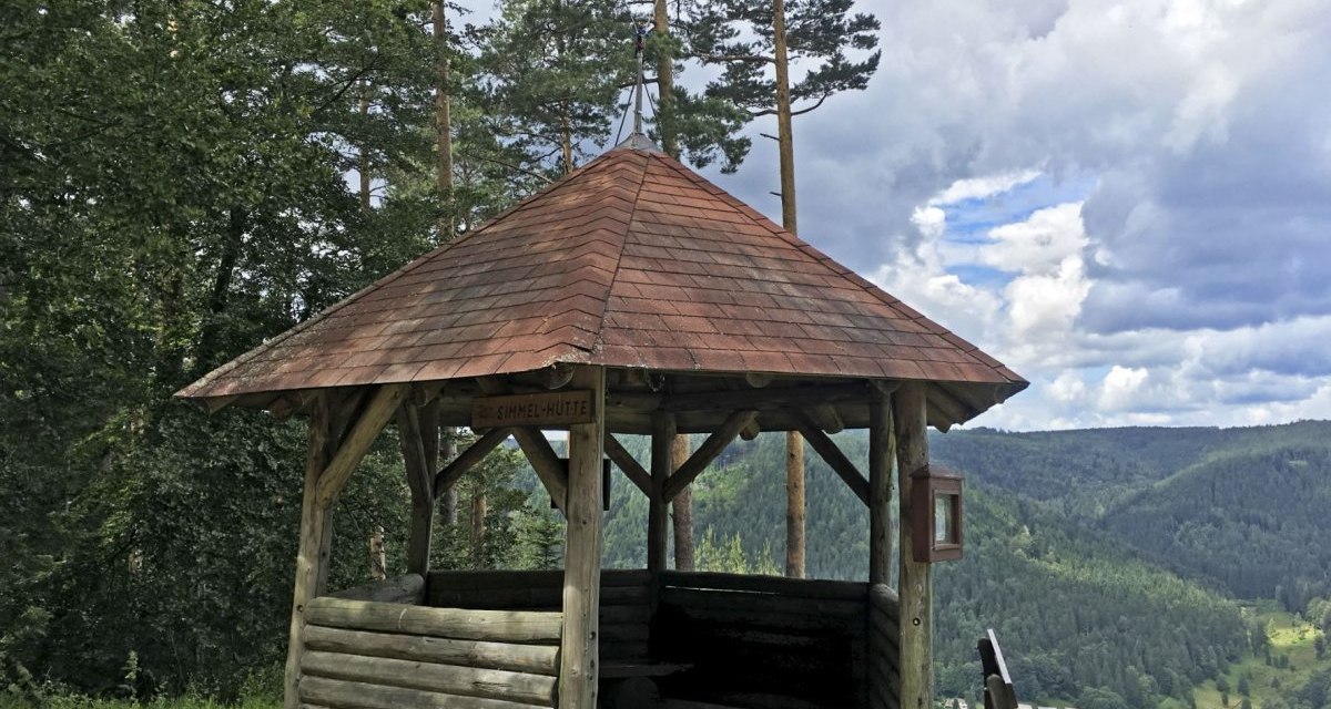 Hölzerne Schutzhütte mit Sitzbank, umgeben von Bäumen, bietet Blick auf ein bewaldetes Tal unter einem bewölkten Himmel., © www.pro-cycl.de Hölzerne Schutzhütte mit Sitzbank, umgeben von Bäumen, bietet Blick auf ein bewaldetes Tal unter einem bewölkten Himmel., © www.pro-cycl.de