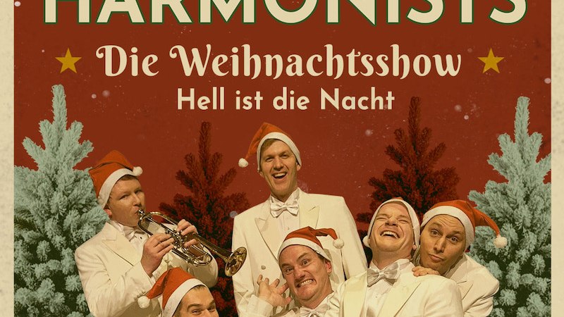 Sechs M&auml;nner in wei&szlig;en Anz&uuml;gen und Weihnachtsm&uuml;tzen posieren fr&ouml;hlich vor einem weihnachtlichen Hintergrund mit Tannenb&auml;umen. Einer h&auml;lt eine Trompete., &copy; RESET Production