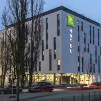 Modernes Hotelgebäude des ibis Styles Stuttgart Vaihingen bei Dämmerung, beleuchtet mit Autos auf der Straße davor., © ibis Styles Stuttgart Vaihingen