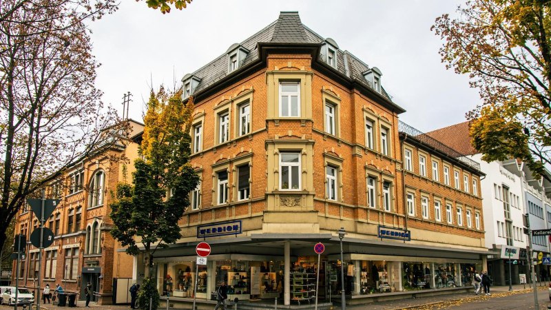 Historische Geb&auml;ude in der Innenstadt von G&ouml;ppingen, umgeben von herbstlichen B&auml;umen. Ein Gesch&auml;ft mit Schaufenstern und Stra&szlig;enschilder sind sichtbar., &copy; Stuttgart-Marketing GmbH, Sarah Schmid