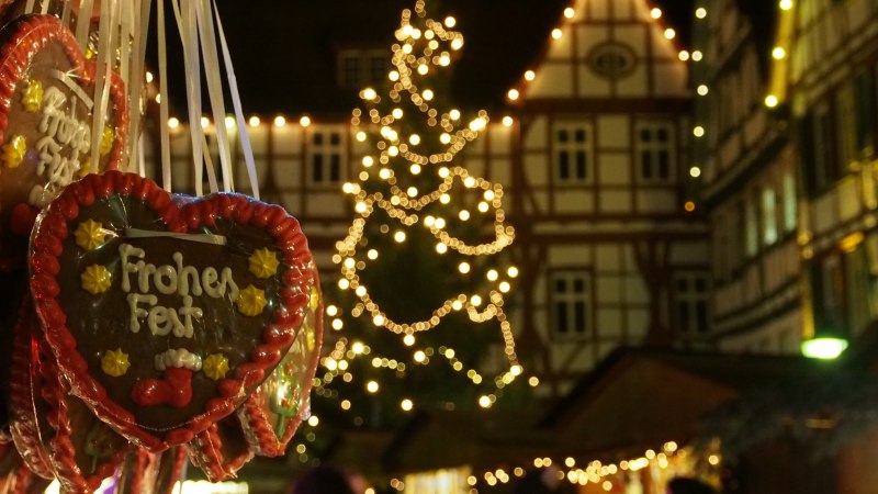 Lebkuchenherzen mit 'Frohes Fest' hängen vor einem beleuchteten Weihnachtsbaum auf dem Bad Uracher Weihnachtsmarkt. Fachwerkhäuser im Hintergrund., © Bad Urach Tourismus Lebkuchenherzen mit 'Frohes Fest' hängen vor einem beleuchteten Weihnachtsbaum auf dem Bad Uracher Weihnachtsmarkt. Fachwerkhäuser im Hintergrund., © Bad Urach Tourismus