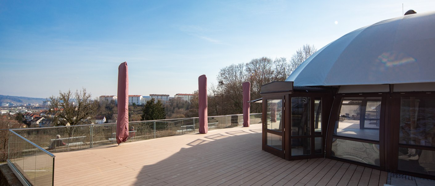 Eine Terrasse mit einem Kuppelgebäude und Blick auf eine Stadt im Hintergrund. Der Himmel ist klar und blau., © Marc Luppa