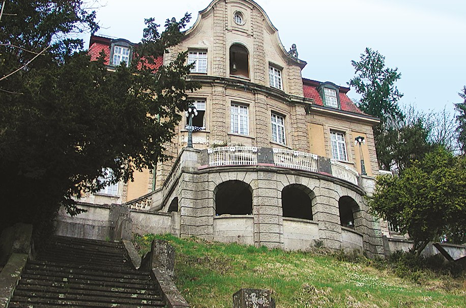 Historische Villa mit geschwungenem Dach, großen Fenstern und einer Treppe im Vordergrund, umgeben von Bäumen und Rasen., © Stuttgart-Marketing GmbH Historische Villa mit geschwungenem Dach, großen Fenstern und einer Treppe im Vordergrund, umgeben von Bäumen und Rasen., © Stuttgart-Marketing GmbH