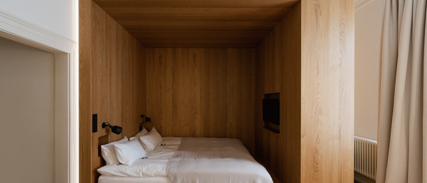 Modernes Schlafzimmer mit Holzverkleidung, eingebautem Bett und kleinem Fernseher. Minimalistisches Design mit warmen Holztönen und schlichter Beleuchtung., © Peter Oliver Wolff / DAS EDITH