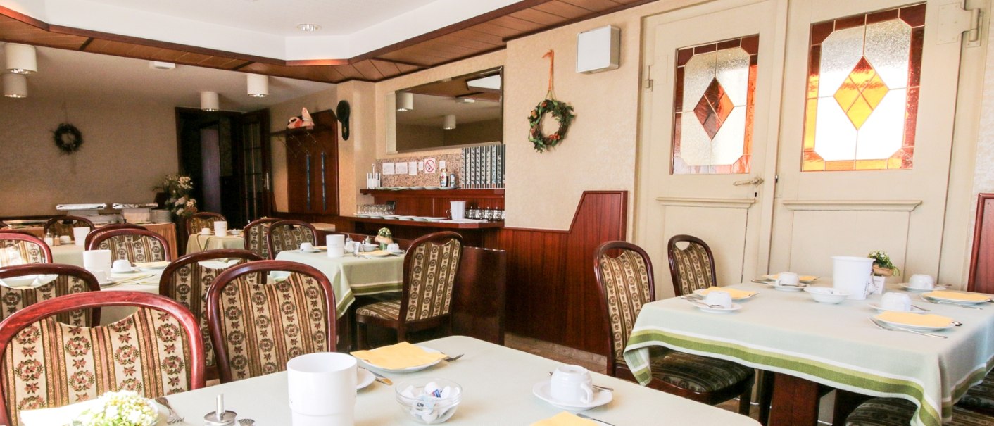 Ein gemütlicher Frühstücksraum mit gedeckten Tischen, Stühlen und dekorativen Elementen. Die Einrichtung wirkt einladend und traditionell., © Ulli Kellenbenz Ein gemütlicher Frühstücksraum mit gedeckten Tischen, Stühlen und dekorativen Elementen. Die Einrichtung wirkt einladend und traditionell., © Ulli Kellenbenz