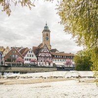 Blick auf N&uuml;rtingen mit Fachwerkh&auml;usern und Kirchturm am Fluss. Bl&uuml;hende B&auml;ume und eine Fischtreppe im Vordergrund., &copy; SMG, Sarah Schmid