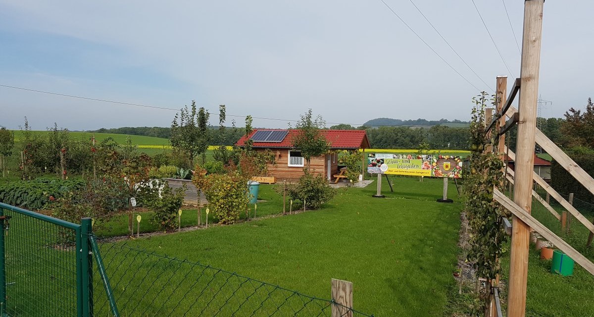 Ein gepflegter Garten mit Rasen, Bäumen und einem Holzhaus. Ein Zaun umgibt das Gelände, im Hintergrund ist ein Banner sichtbar., © Remstal Tourismus e.V. Ein gepflegter Garten mit Rasen, Bäumen und einem Holzhaus. Ein Zaun umgibt das Gelände, im Hintergrund ist ein Banner sichtbar., © Remstal Tourismus e.V.