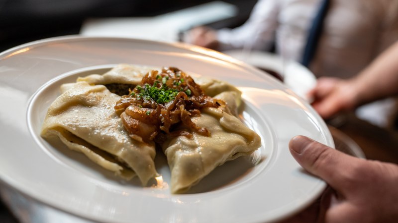 Ein Teller mit Maultaschen, garniert mit Röstzwiebeln und Schnittlauch, wird in einem Restaurant serviert., © Stuttgart-Marketing GmbH, Martina Denker