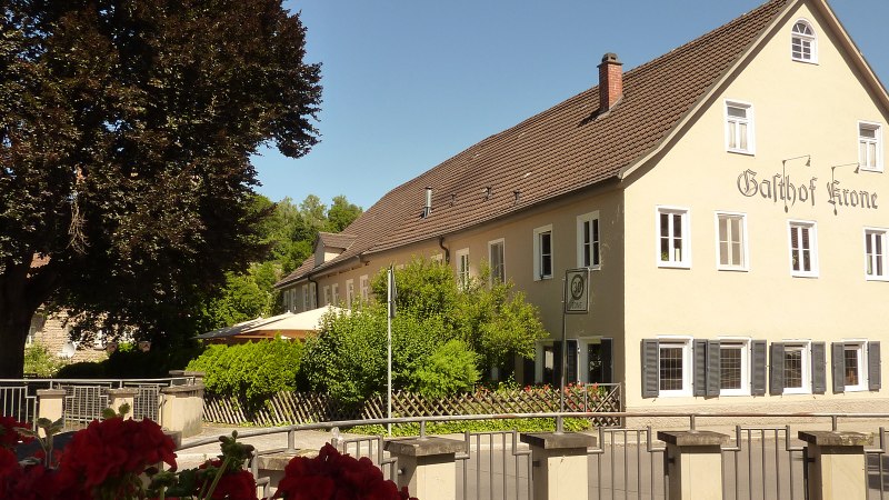 Der Gasthof Krone, ein großes Gebäude mit gelber Fassade und braunem Dach, umgeben von Bäumen und einem Garten. Ein Stoppschild ist sichtbar., © Gasthof Krone, Matthias Gugeler Der Gasthof Krone, ein großes Gebäude mit gelber Fassade und braunem Dach, umgeben von Bäumen und einem Garten. Ein Stoppschild ist sichtbar., © Gasthof Krone, Matthias Gugeler