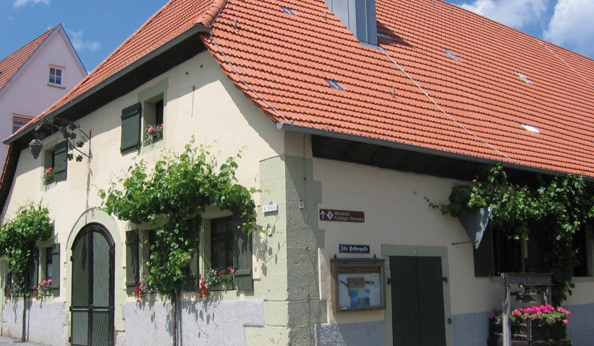 Historisches Gebäude mit rotem Ziegeldach, grünen Fensterläden und Weinreben an der Fassade. Ein Schild weist auf die "Alte Kelterstraße" hin., © Land der 1000 Hügel - Kraichgau-Stromberg Historisches Gebäude mit rotem Ziegeldach, grünen Fensterläden und Weinreben an der Fassade. Ein Schild weist auf die "Alte Kelterstraße" hin., © Land der 1000 Hügel - Kraichgau-Stromberg