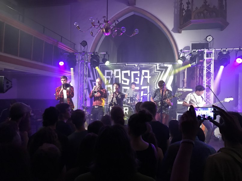 Eine Band spielt auf einer Bühne mit bunten Lichtern. Das Publikum schaut zu, während die Musiker verschiedene Instrumente spielen., © Stadt Nürtingen Eine Band spielt auf einer Bühne mit bunten Lichtern. Das Publikum schaut zu, während die Musiker verschiedene Instrumente spielen., © Stadt Nürtingen