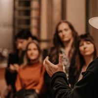 Ein Mann mit Hut spricht zu einer Gruppe von Menschen in einem Keller. Die Zuhörer wirken interessiert., © Fellbacher Weingärtner eG Ein Mann mit Hut spricht zu einer Gruppe von Menschen in einem Keller. Die Zuhörer wirken interessiert., © Fellbacher Weingärtner eG