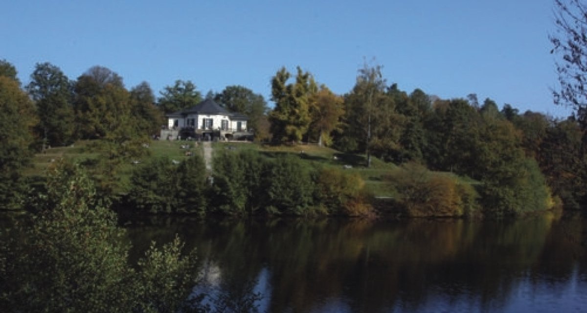 Das B&auml;renschl&ouml;ssle steht auf einem H&uuml;gel, umgeben von B&auml;umen, mit einem See im Vordergrund unter klarem, blauem Himmel., &copy; Sindelfingen - Stuttgart-Marketing GmbH