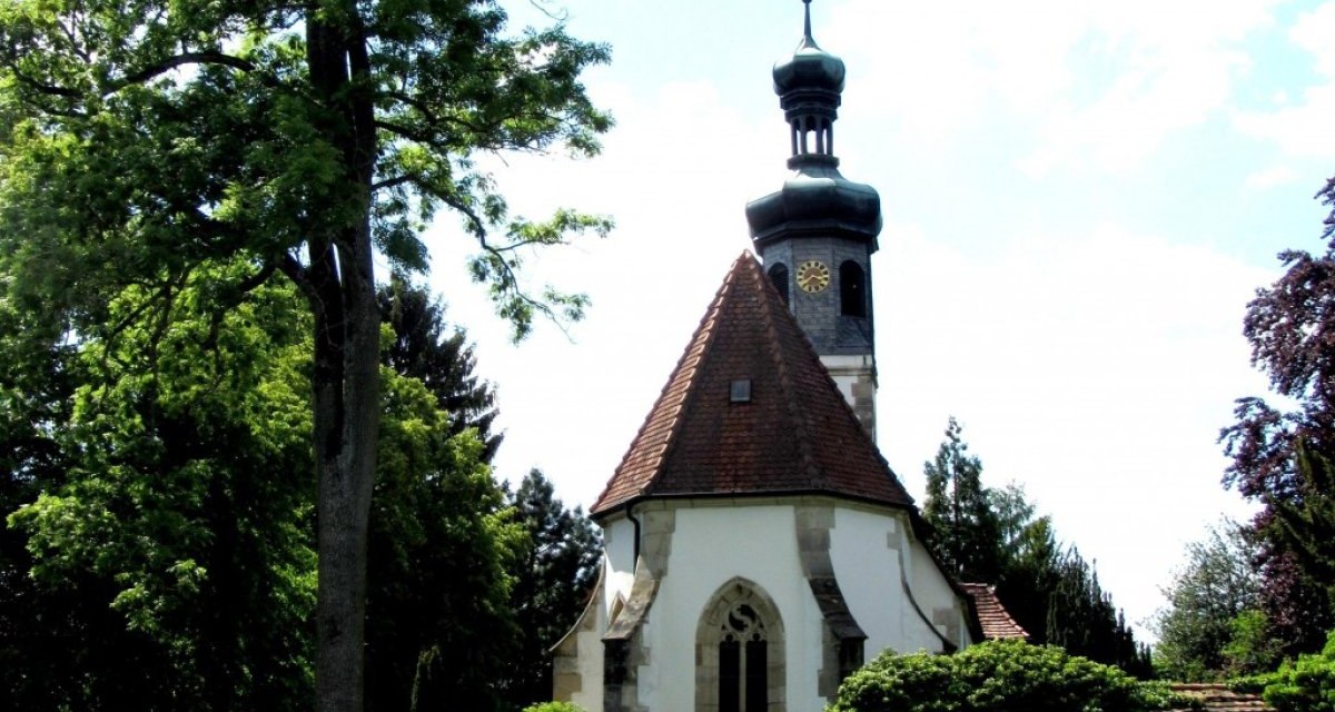 Historisches Gebäude mit Turm und Uhr, umgeben von Bäumen und einer Steinmauer. Der Himmel ist teils bewölkt., © Aktiv-Region Stuttgart Historisches Gebäude mit Turm und Uhr, umgeben von Bäumen und einer Steinmauer. Der Himmel ist teils bewölkt., © Aktiv-Region Stuttgart