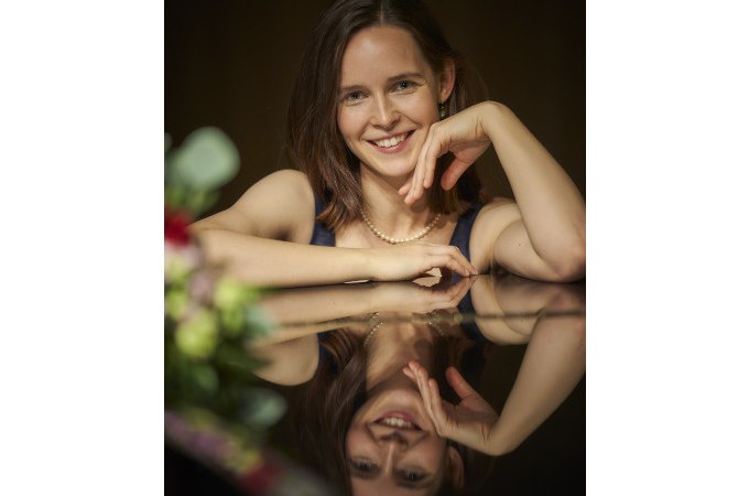 Eine Frau mit braunen Haaren und Perlenkette lehnt sich lächelnd auf einen Tisch. Ihr Spiegelbild ist auf der glänzenden Oberfläche sichtbar., © WTM GmbH Waiblingen