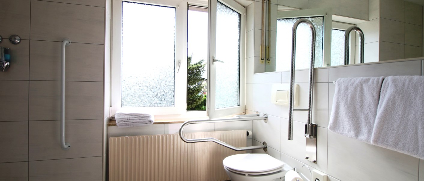 Barrierefreies Badezimmer mit Haltegriffen, bodengleicher Dusche, offenem Fenster und Handtüchern. Geeignet für Gäste mit eingeschränkter Mobilität., © TOMAS Barrierefreies Badezimmer mit Haltegriffen, bodengleicher Dusche, offenem Fenster und Handtüchern. Geeignet für Gäste mit eingeschränkter Mobilität., © TOMAS
