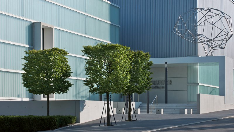 Moderne Architektur des Schauwerks Sindelfingen mit Glasfassade, Bäumen und einer abstrakten Skulptur auf dem Dach., © Stuttgart-Marketing GmbH Moderne Architektur des Schauwerks Sindelfingen mit Glasfassade, Bäumen und einer abstrakten Skulptur auf dem Dach., © Stuttgart-Marketing GmbH