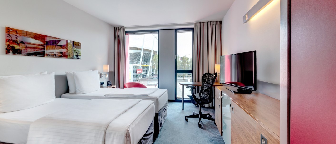 Modernes Hotelzimmer mit zwei Einzelbetten, Schreibtisch, Stuhl und Fernseher. Große Fenster bieten Blick nach draußen. Helle, freundliche Einrichtung., © Hilton Garden Inn Stuttgart Neckarpark Modernes Hotelzimmer mit zwei Einzelbetten, Schreibtisch, Stuhl und Fernseher. Große Fenster bieten Blick nach draußen. Helle, freundliche Einrichtung., © Hilton Garden Inn Stuttgart Neckarpark