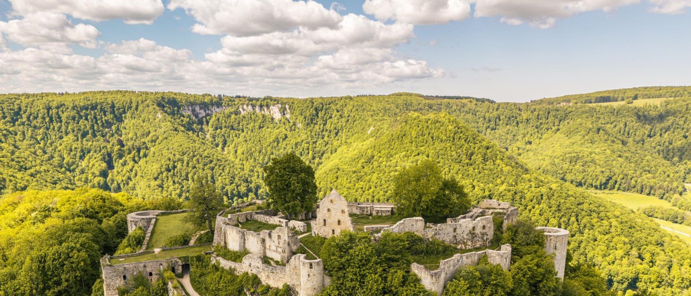 Luftaufnahme der Burgruine Hohenurach, umgeben von dichten, grünen Wäldern unter einem bewölkten Himmel., © Stuttgart-Marketing GmbH, Sarah Schmid Luftaufnahme der Burgruine Hohenurach, umgeben von dichten, grünen Wäldern unter einem bewölkten Himmel., © Stuttgart-Marketing GmbH, Sarah Schmid
