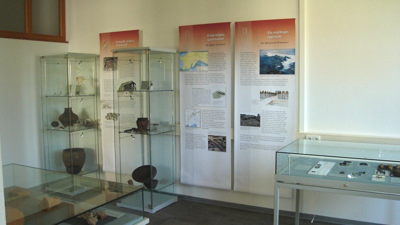 Innenansicht des Keltenmuseums Grabenstetten mit Vitrinen, die Artefakte zeigen, und Informationstafeln an der Wand. Innenansicht des Keltenmuseums Grabenstetten mit Vitrinen, die Artefakte zeigen, und Informationstafeln an der Wand.