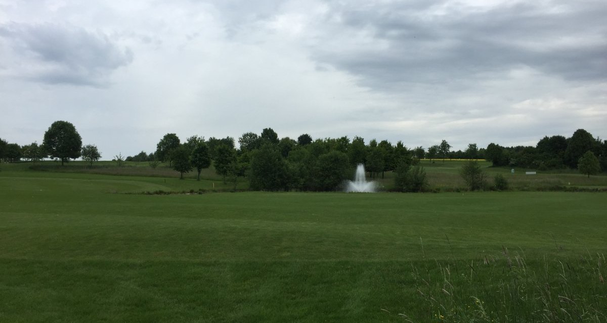 Weitl&auml;ufiger Golfplatz mit saftigem Gr&uuml;n, B&auml;umen und einem Springbrunnen. Der Himmel ist bew&ouml;lkt, was eine ruhige Atmosph&auml;re schafft., &copy; www.pro-cycl.de